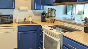 Une cuisine moderne avec des meubles bleus, une cuisinière blanche et un four à micro-ondes noir.