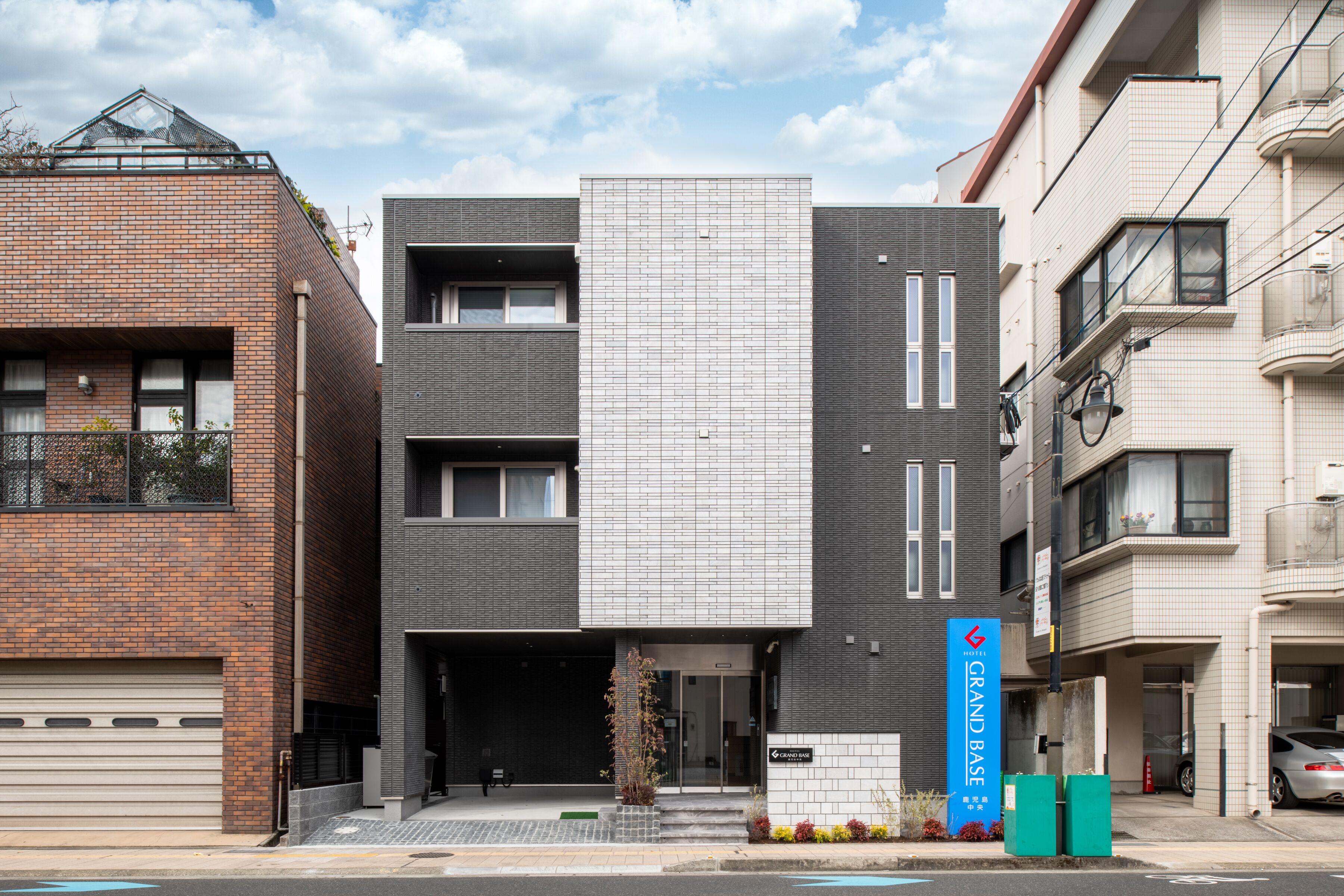 A modern building with a brick facade, a large white panel, and a sign reading "Grand Base".