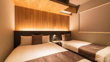 Habitación de hotel con dos camas, cabecero de madera, lámpara de pared y ventana con persianas.