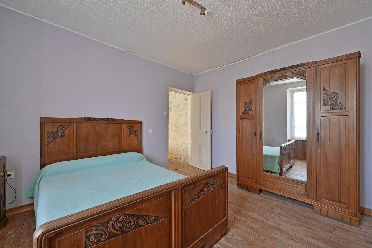 Une chambre à coucher avec un lit en bois, une armoire et un miroir.