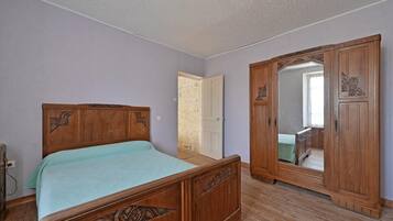 Une chambre à coucher avec un lit en bois, une armoire et un miroir.