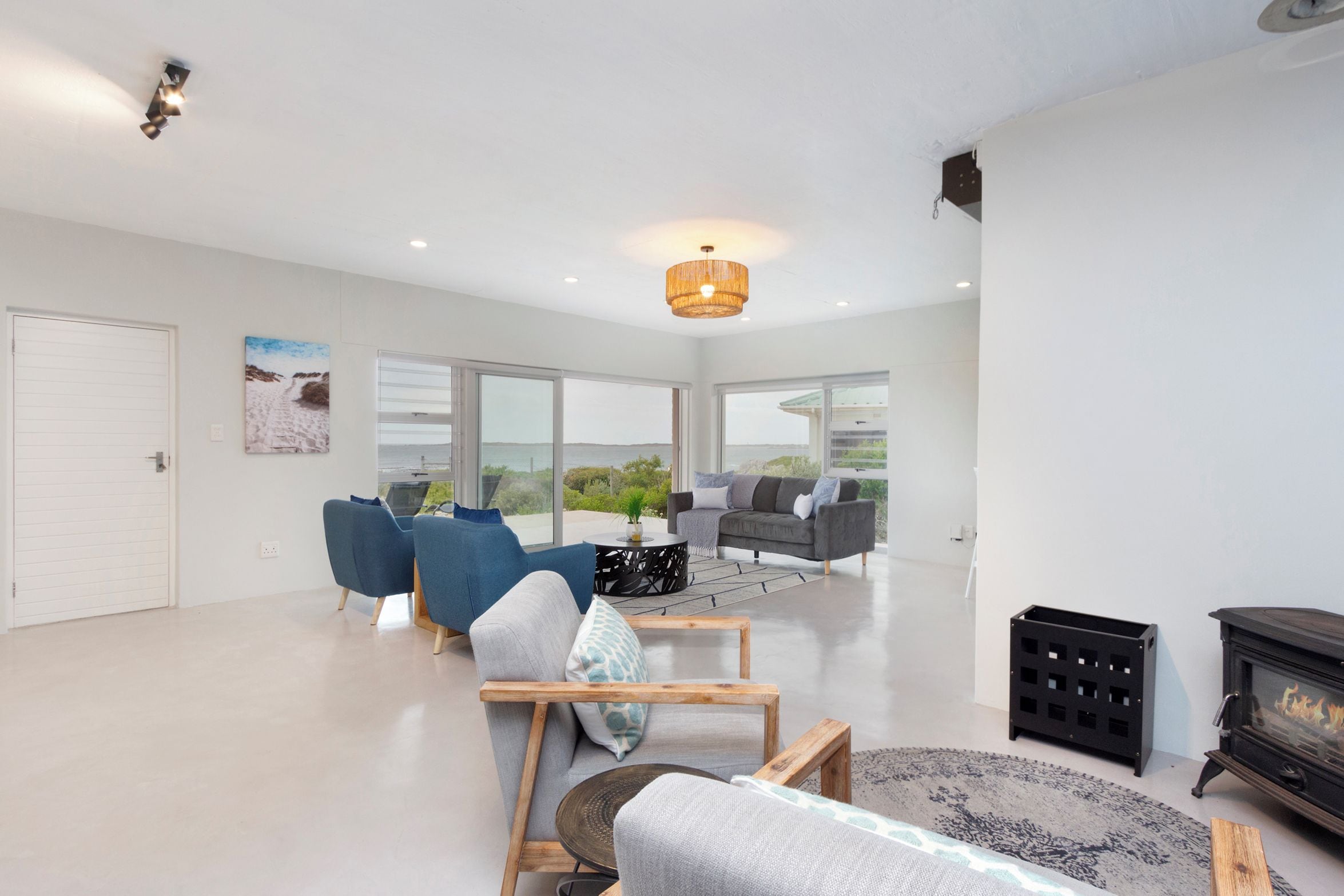 A spacious living room with a fireplace, large windows, and a modern chandelier.