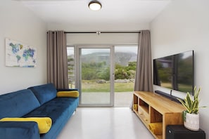 A modern living room with a blue sofa, a wooden TV stand, and a large TV.