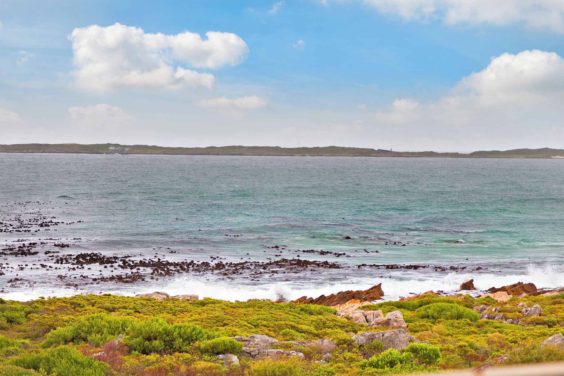 A coastal landscape with rocky terrain and greenery.