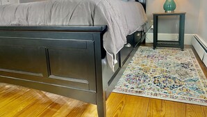 A bedroom with a dark wooden bed, a patterned rug, and two bedside lamps.
