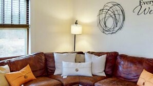 A living room with a brown leather sectional sofa, a wooden coffee table, and a lamp.