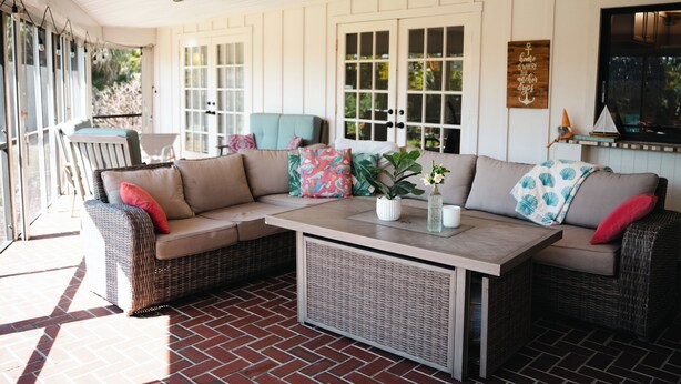 A covered patio area with wicker furniture, a table, and a view of the outdoors. - Tiki Retreat (North Fort Myers)