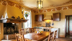 A traditional kitchen with a dining table, chairs, and a fireplace.