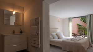 Un bagno moderno con uno specchio grande, un portasciuga-asciugamani e un comodino. La stanza presenta un letto con copripiumino e cuscini color beige.