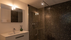 Un bagno moderno con un mobile lavabo bianco, un vaso verde e una doccia con piastrelle a mosaico.
