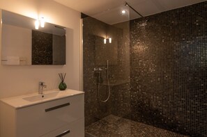 A modern bathroom with a white vanity, a green vase, and a shower with mosaic tiles. - Villa T3 du Domaine Zuria (Bonifacio)