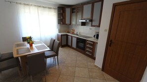 A compact kitchen with a dining area, featuring a table with chairs, a stove, and a sink.