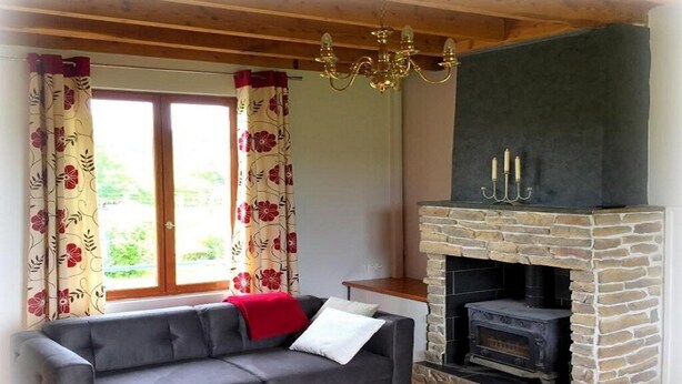 Una sala de estar con sofá, chimenea de piedra y ventana con cortinas florales.