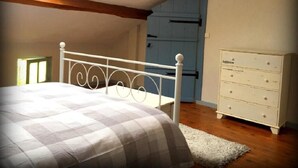 Un dormitorio con una cama, un aparador y una puerta azul al fondo.