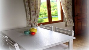 Una mesa blanca con tres manzanas y una ventana con cortinas.
