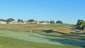 A golf course with a clubhouse, houses in the background, and a clear sky. - Beautiful golf course views, with golf cart access to the villages (Summerfield)