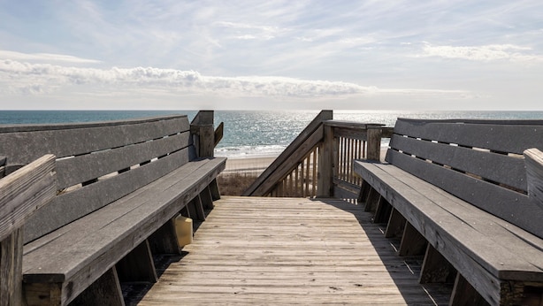 Un muelle de madera que conduce a una playa, con vista despejada al océano.