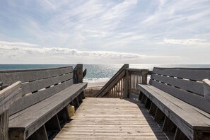 Une promenade en bois qui mène à une plage d’où l’on a une vue dégagée sur l’océan.