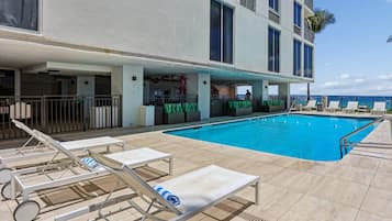 Un área de piscina con tumbonas y un bar.