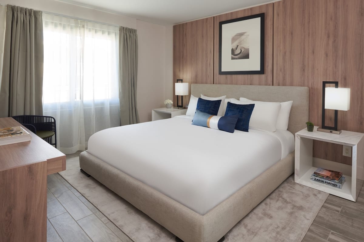 A modern hotel room with a large bed, bedside tables, a desk, and a chair.
