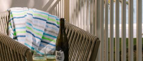 A wicker chair with a striped towel and a bottle of Big Salt wine on a tray.