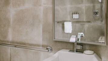 A bathroom with a white sink, a mirror, and a shower.