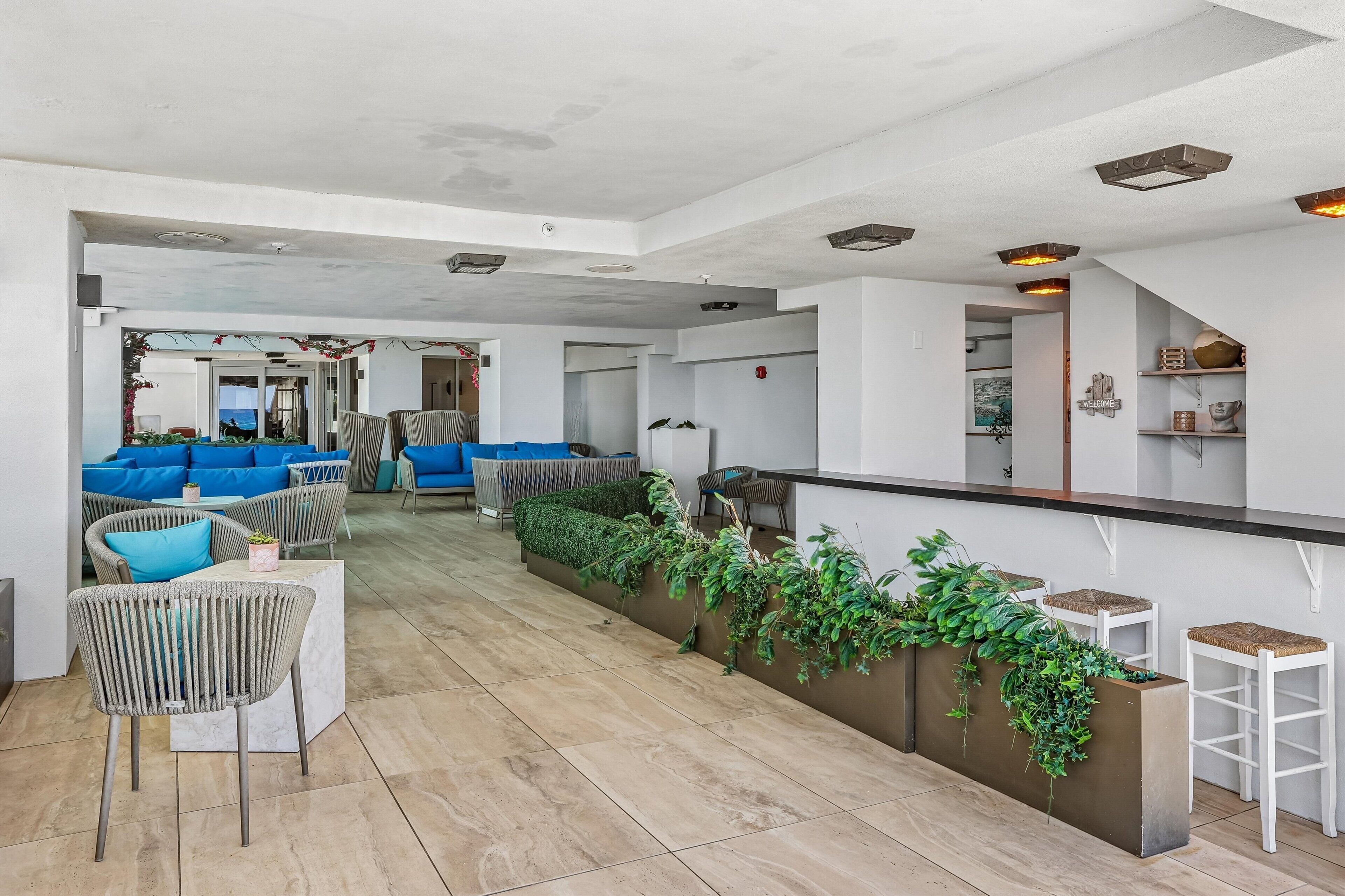 Un área de descanso moderna con asientos, un bar y vista al mar.