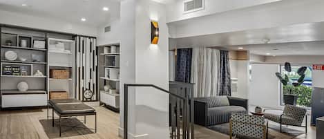 A modern hotel lobby with a staircase, seating area, and a view of the outside.