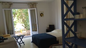 Una habitación con cama, escritorio, silla, televisión y ventana con cortinas.