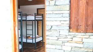 Une pièce avec des lits superposés, un mur en pierre et un plancher en bois.