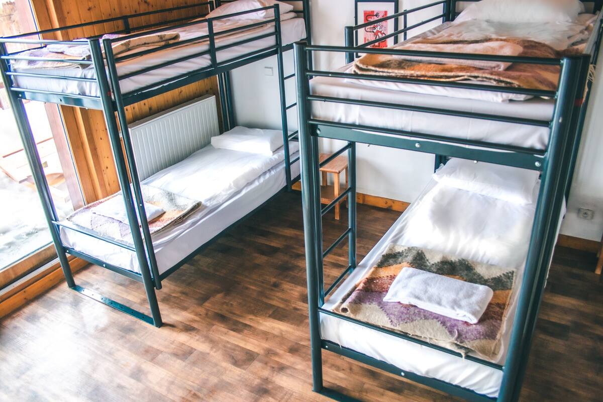 Bunk beds with wooden floors and a small wooden stool.