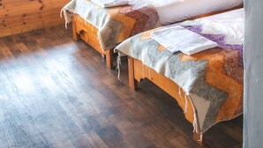 Une chambre dans un chalet en bois, avec deux lits, une fenêtre et un radiateur.