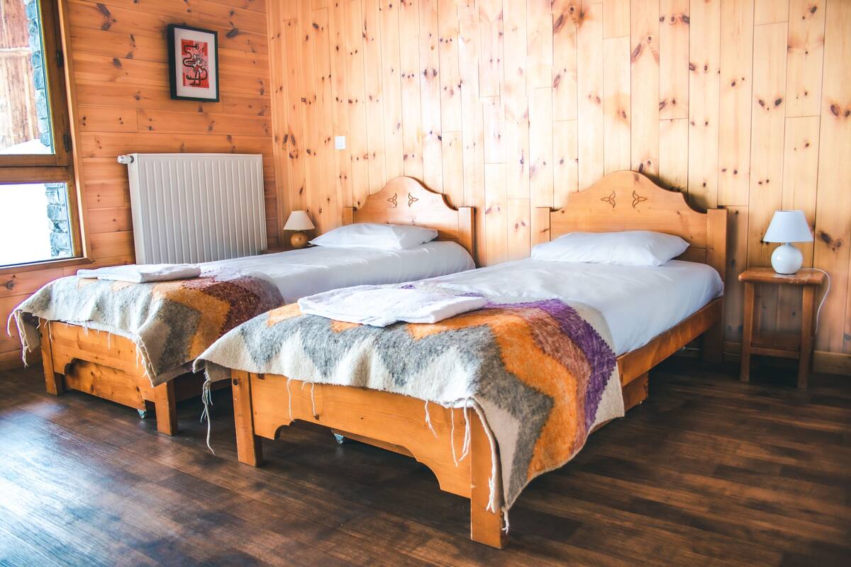 A room with two wooden beds, a radiator, and a framed picture on the wall.