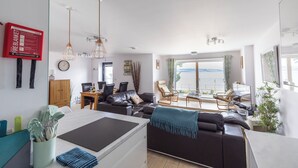 Een moderne woonkamer met een bank, eethoek en uitzicht op zee.