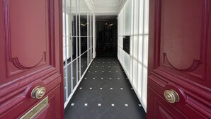 A hallway with red doors, white trim, and a tiled floor.