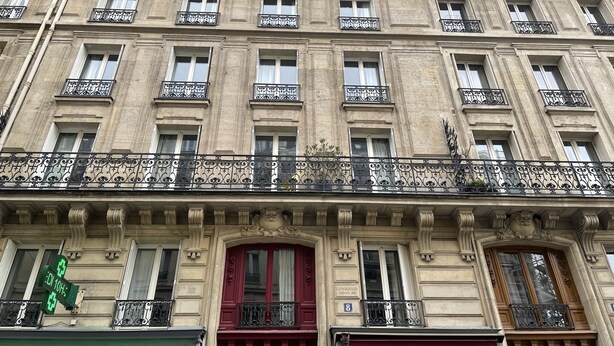 A historic building with multiple balconies, large windows, and ornate iron railings.