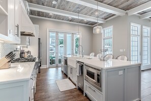 Une cuisine moderne avec des meubles blancs, un grand îlot central et un plafond en bois.