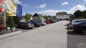 A parking lot with several cars, flags, and buildings in the background. - Vacation apartment in Haus Wiesenblume: Apartment 1 (Willingen-Usseln)