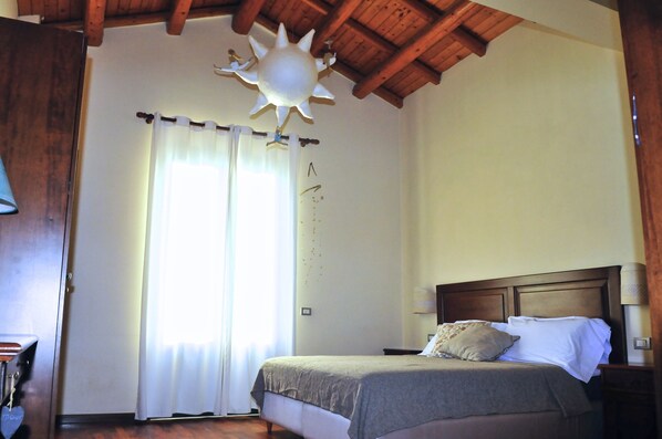 A bedroom with a wooden ceiling, a bed with a headboard, a nightstand, and a wall-mounted lamp. - Terrazza sul Castello Ursino by Wonderful Italy (Catania)