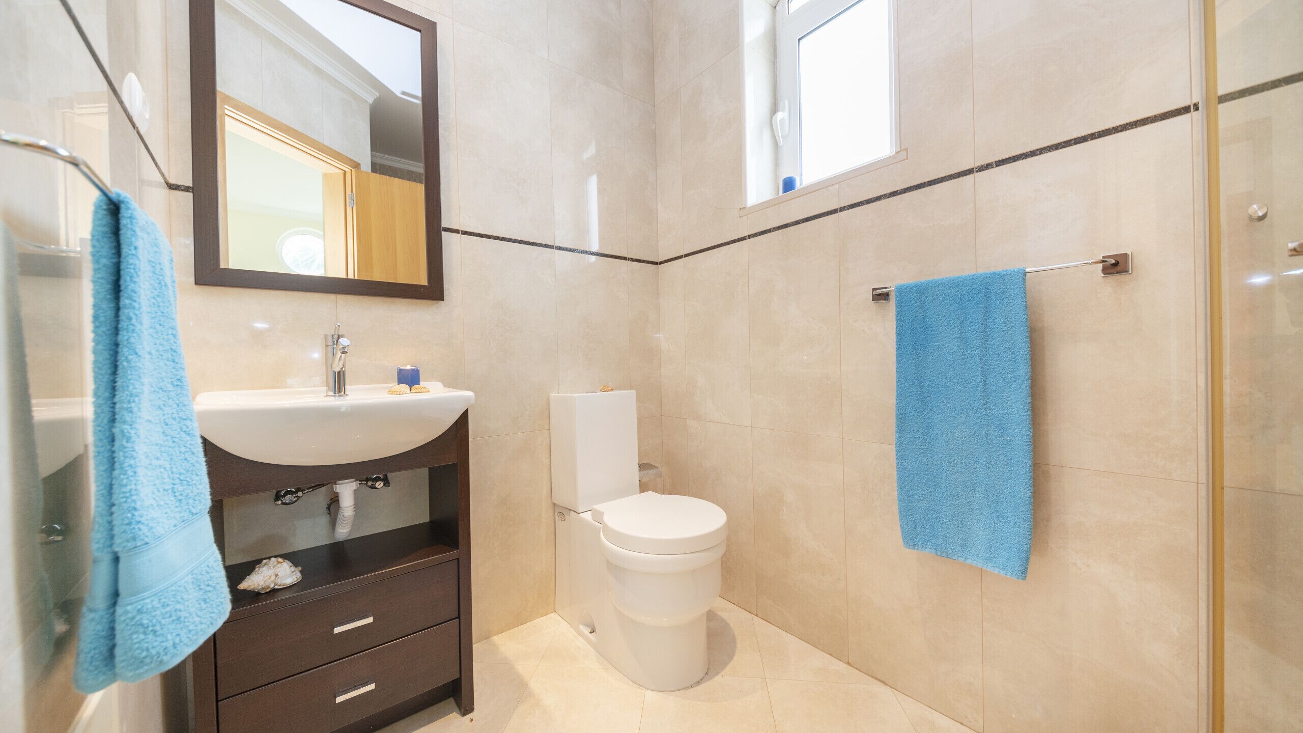 A bathroom with a sink, mirror, toilet, and a towel rack.