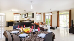 A modern living space with a dining area, kitchen, and a large sliding glass door to a garden. - Villa with BBQ and heatable pool in Armação de Pêra (Armação de Pêra)