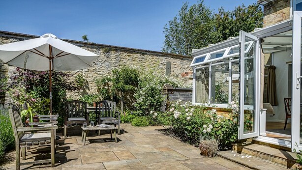 A patio with stone flooring, wooden furniture, and a white umbrella. - High Trees Blenheim View | Woodstock Holiday Let | 3 Beds & Sleeps 5 (Woodstock)