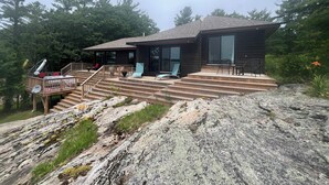 Een moderne houten vakantiewoning met een terras, buitenmeubels en een trap naar de ingang.