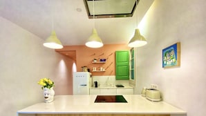 A modern kitchen with a central island, bar stools, a refrigerator, and a green cabinet. - Tyche Apartment Barcelona (Barcelona)