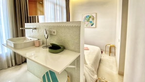 A modern bathroom with a white vanity, a mirror, a sink, and a small stool. - Tyche Apartment Barcelona (Barcelona)