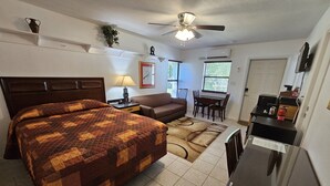 A hotel room with a large bed, a ceiling fan, a desk with a chair, a small table with chairs, and a window with blinds. - Great quiet and comfortable, South Central Lakeland location. (Lakeland)