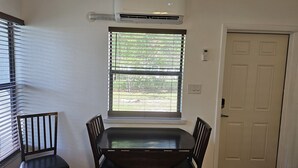 A dining area with a table and chairs, a window with blinds, an air conditioning unit, and a door. - Great quiet and comfortable, South Central Lakeland location. (Lakeland)