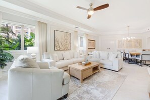 Un salon spacieux comprenant un canapé d’angle, une table basse et un coin repas avec des chaises.