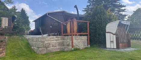 A wooden cabin with a stone foundation, a metal structure, and a small shed.