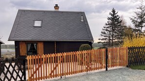 A house with a sloped roof, a wooden fence, and a gravel driveway.